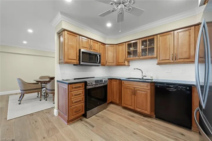 Kitchen featuring wood-finish flooring, recessed lighting, crown molding, a ceiling fan, and stainless steel appliances