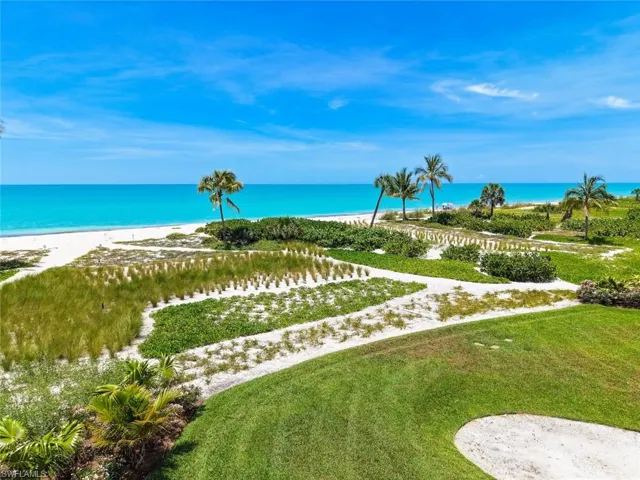 Expansive beach and ocean scenery featuring white sand, tropical foliage, mature palm trees, and manicured green spaces