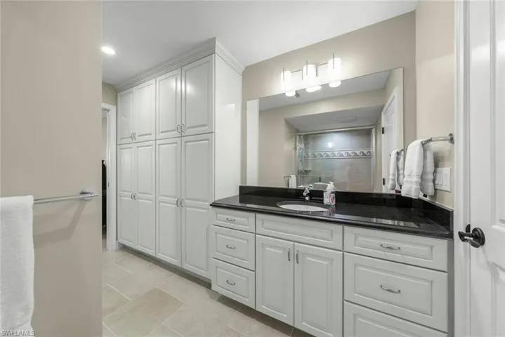 Spacious bathroom featuring an expansive vanity with double sinks and a dark countertop