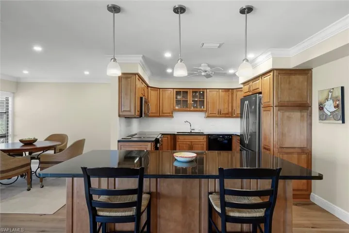 Kitchen featuring wood-finish cabinetry, black appliances, dark countertops, and a white tile backsplash