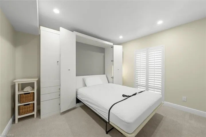 Integrated wall unit with a fold-down bed, white cabinetry, and recessed lighting