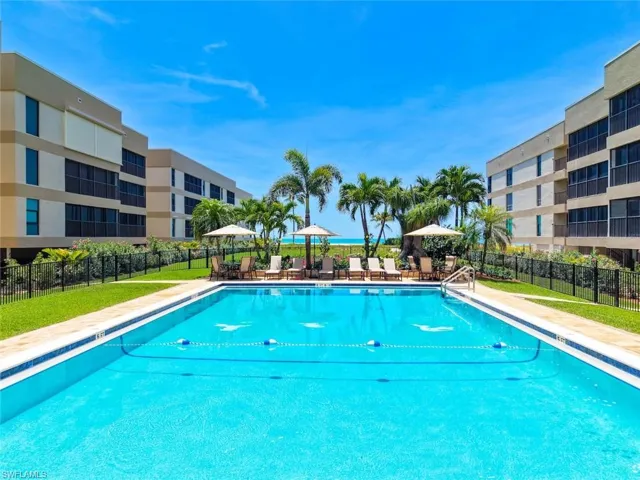 Expansive community pool bordered by a surrounding patio and manicured lawn