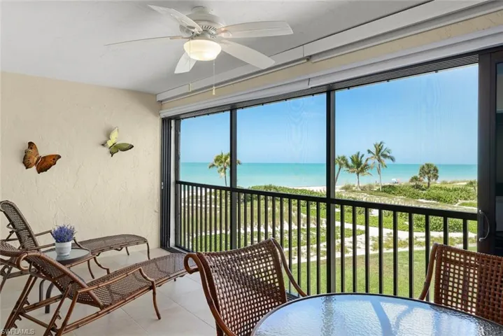Screened balcony featuring a ceiling fan with integrated lighting, textured wall finish, and tiled flooring