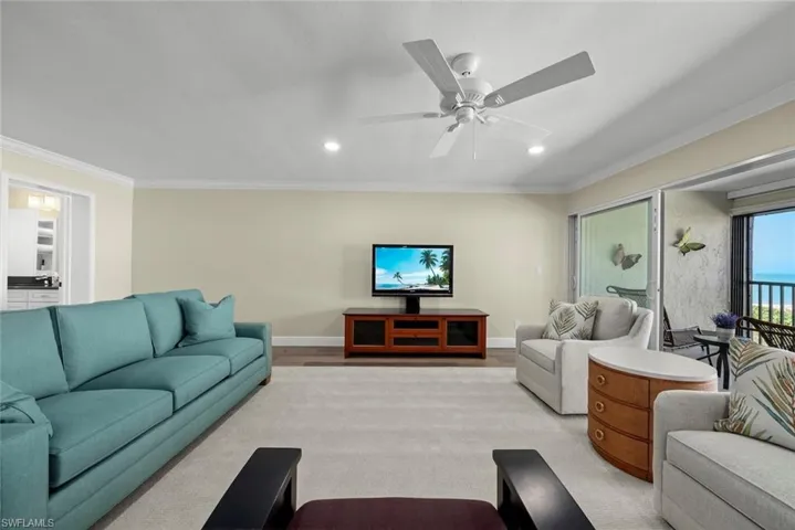 Living area featuring light-colored walls, crown molding, and wood-finish flooring