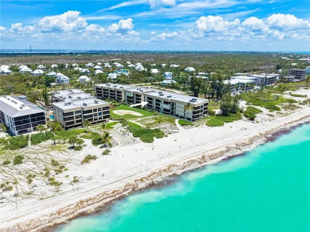 Beachfront condominiums featuring direct water access, white sand beach, manicured green spaces, and a swimming pool