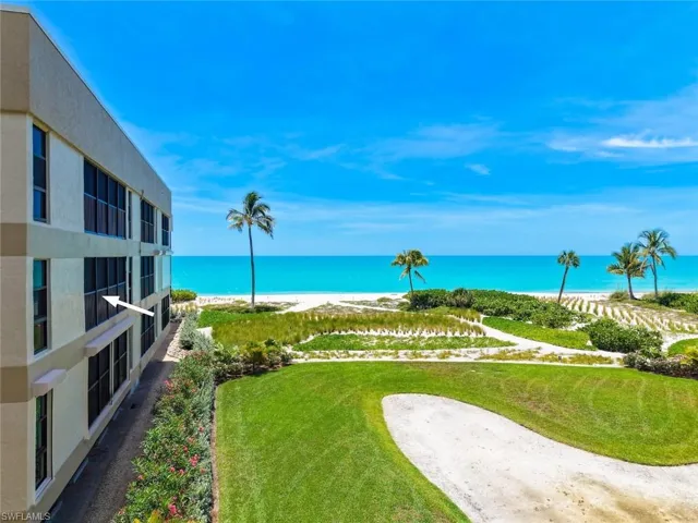 Expansive golf course and beach scenery featuring a sand trap, manicured lawn, and palm trees