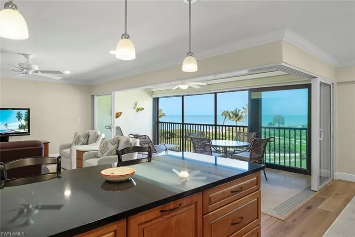 Open-concept living area with a kitchen island featuring a dark countertop, wood-finish cabinetry, and pendant lighting