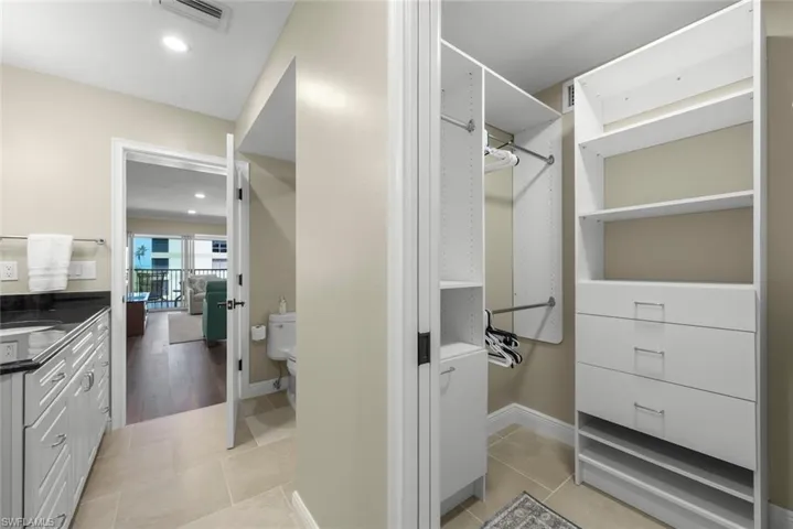 Custom closet system with white shelving, multiple hanging rods, and integrated drawers