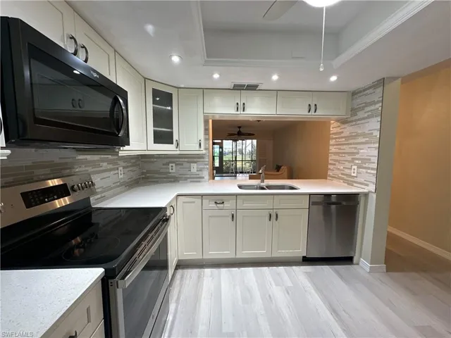 Kitchen featuring stainless steel appliances, backsplash, a raised ceiling, and sink
