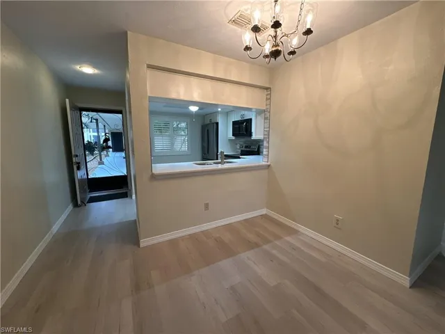 Unfurnished dining area with wood-type flooring, sink, and a chandelier