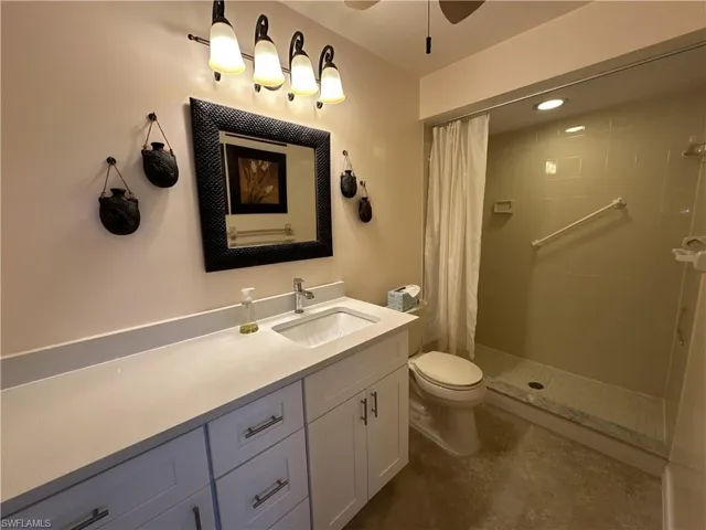 Bathroom featuring toilet, vanity, ceiling fan, and a shower with shower curtain