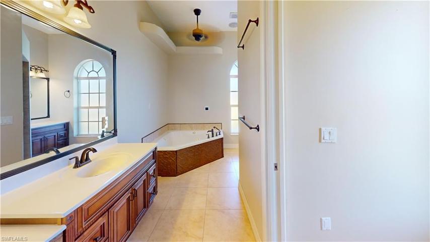 primary on suite bathroom showing soaking jetting tub, one sink with make-up vanity