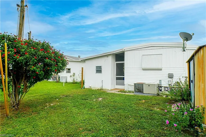 Rear view of property with cooling unit and a yard