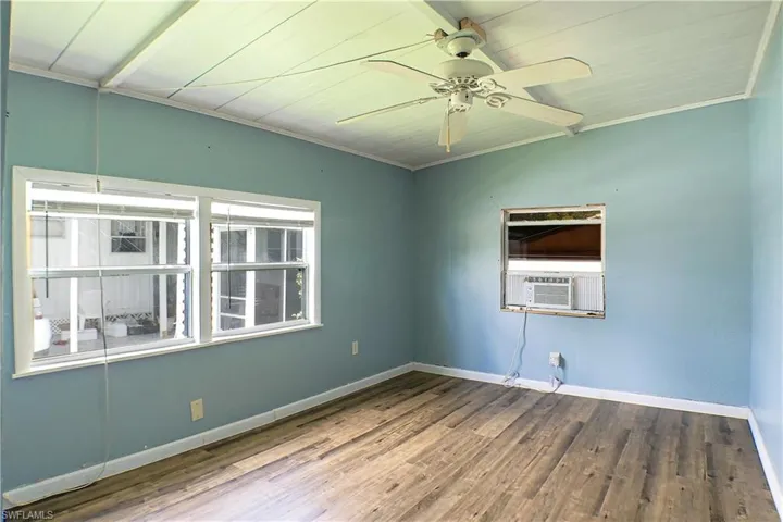 Empty room featuring plenty of natural light, hardwood / wood-style flooring, cooling unit, and ceiling fan