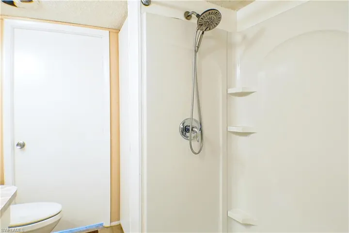 Bathroom featuring a shower, toilet, and a textured ceiling