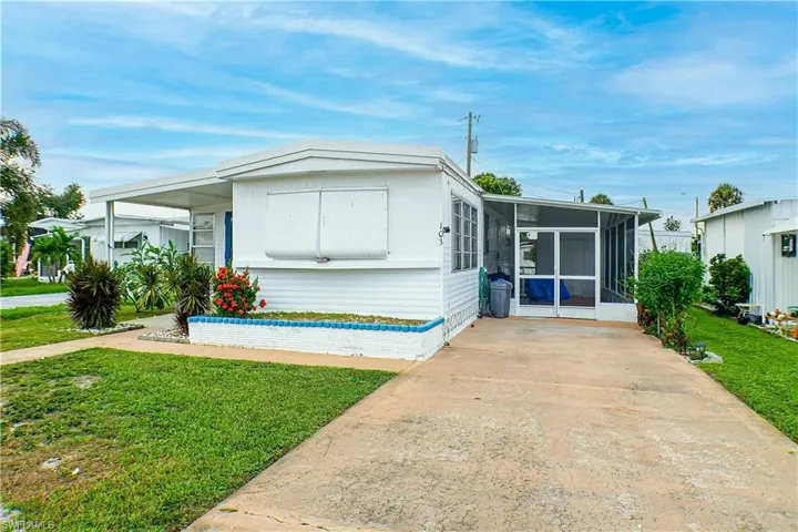 Manufactured / mobile home featuring a carport, a front lawn, and a sunroom