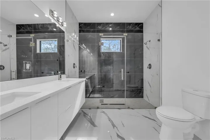 Full bath featuring light marble finish flooring, double vanity, a marble finish shower, and recessed lighting