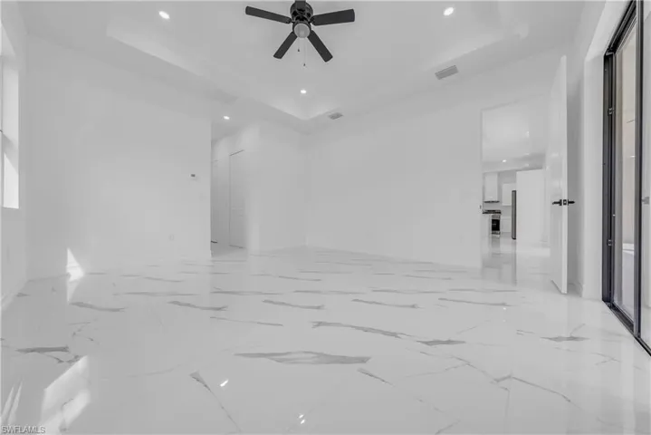 Unfurnished room featuring a raised ceiling, recessed lighting, light marble finish floors, and ceiling fan