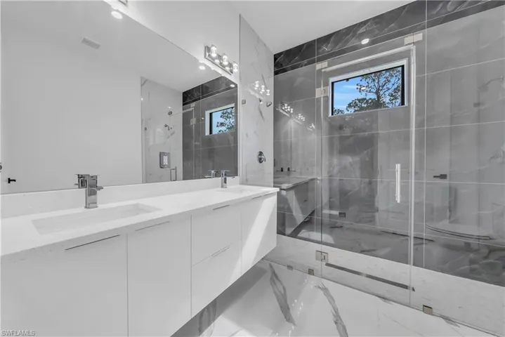 Full bathroom featuring marble tiled floors, double vanity, and a marble finish shower