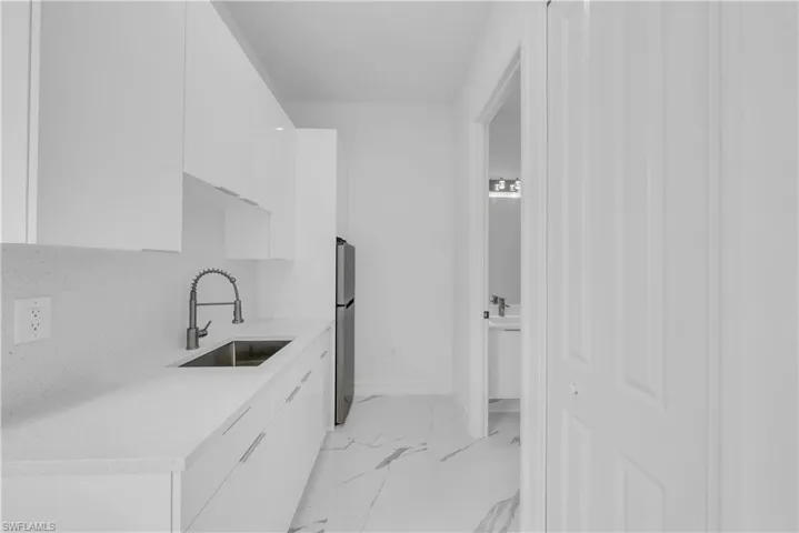 Washroom with a sink and light marble finish floors