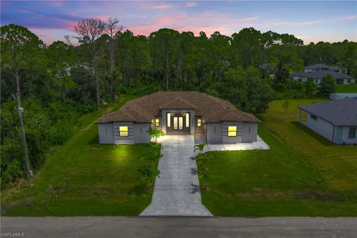 View of front of property featuring driveway, a yard, and stucco siding