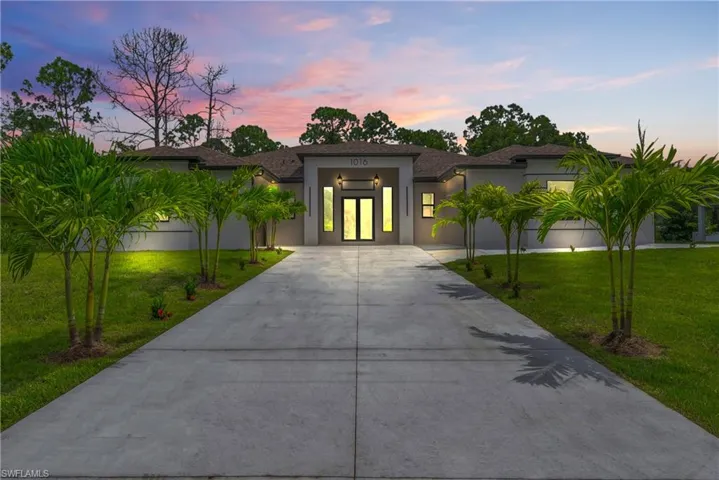 View of front of house with concrete driveway, a front yard, stucco siding, and roof with shingles