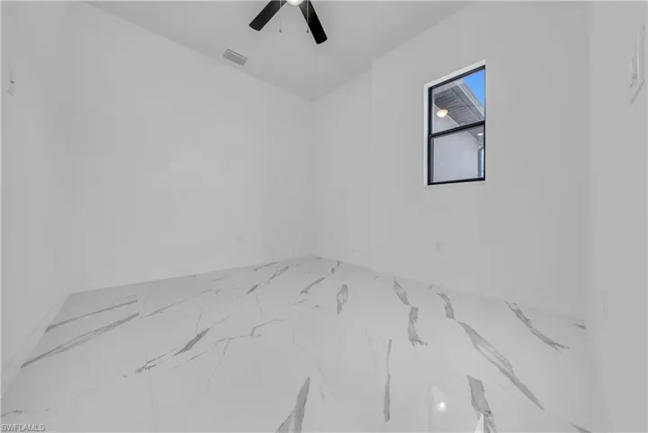 Spare room featuring marble look tiles and ceiling fan