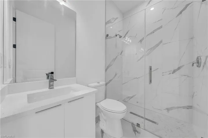 Bathroom featuring vanity, a marble finish shower, and marble finish flooring