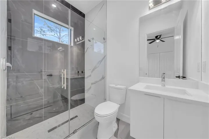 Bathroom featuring a marble finish shower, vanity, and a ceiling fan