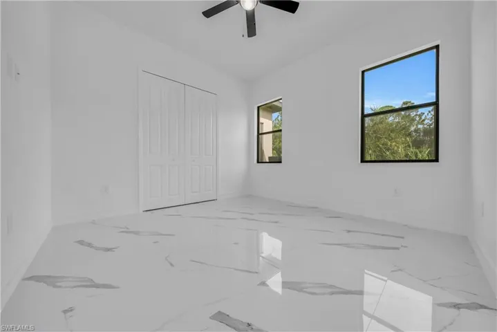 Unfurnished bedroom with light marble finish floors, ceiling fan, and a closet