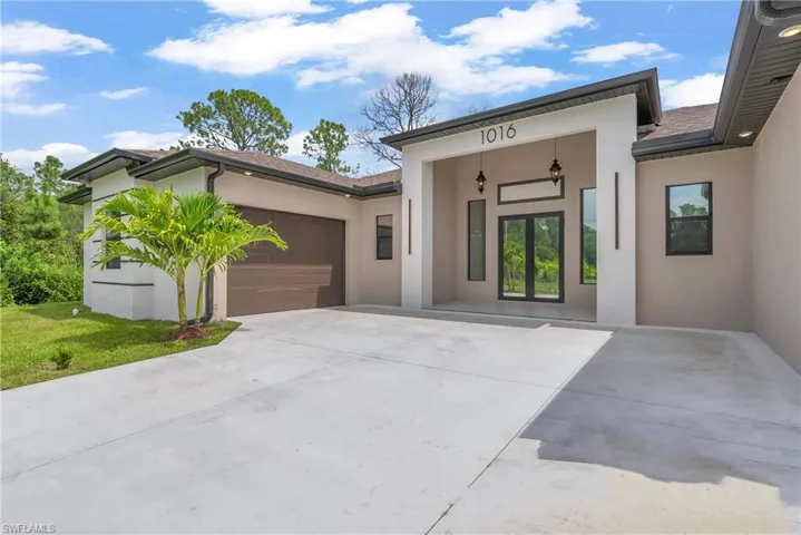 View of front of home with stucco siding, concrete driveway, and a garage