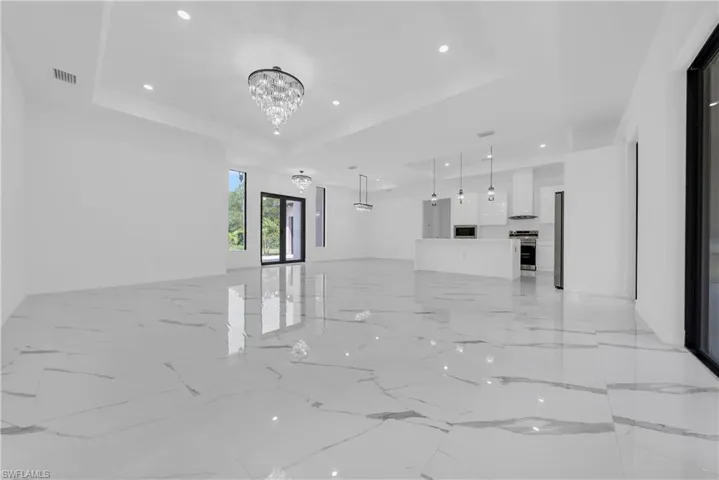 Unfurnished room with recessed lighting, a raised ceiling, light marble finish floors, and a chandelier