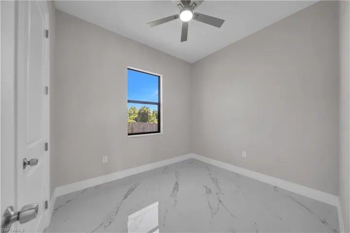 Room featuring marble-look flooring, light gray wall paint, and a modern ceiling fan with integrated lighting
