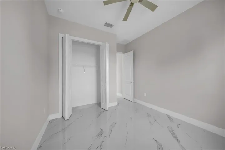 Spacious room featuring large format marble-look tile flooring, light gray wall paint, and white baseboards