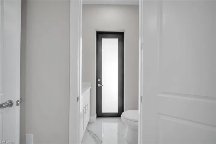 Modern bathroom with a white vanity featuring shaker-style cabinetry, a white countertop, and contemporary hardware