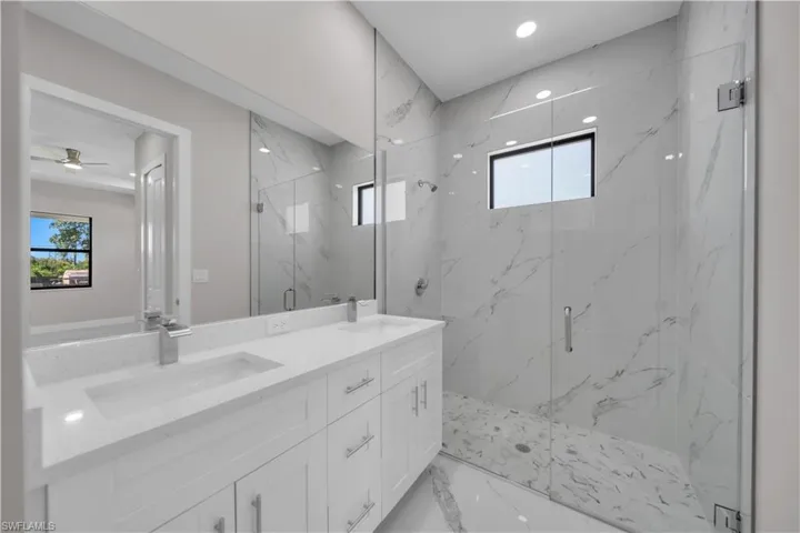 Modern bathroom featuring a dual vanity with white cabinetry and light-toned countertops