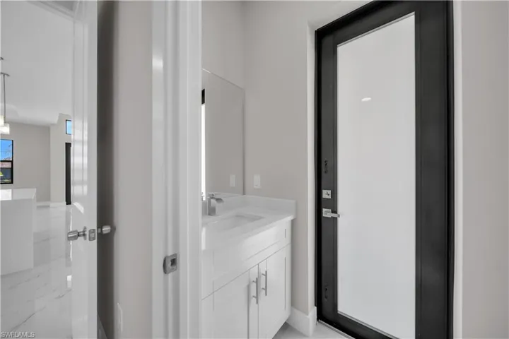 Contemporary bathroom vanity with white cabinetry, integrated sink, and brushed nickel faucet