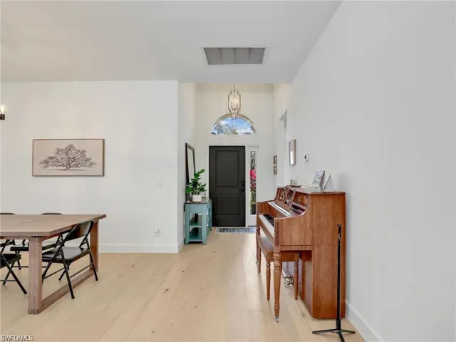 Entryway featuring light wood-style floors, a chandelier, and a towering ceiling