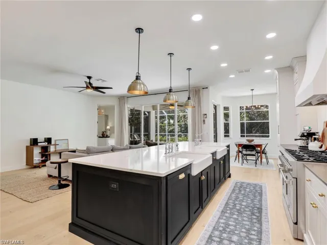 Kitchen with dark cabinets, hanging light fixtures, range with two ovens, recessed lighting, and white cabinetry