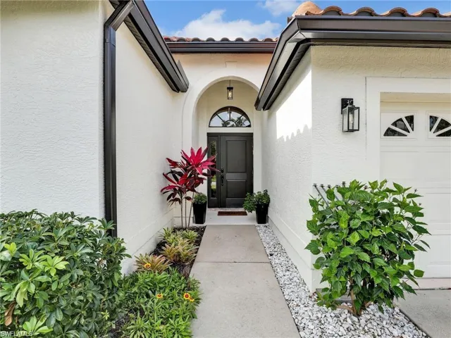 Entrance to property featuring a tiled roof, stucco siding, and a garage
