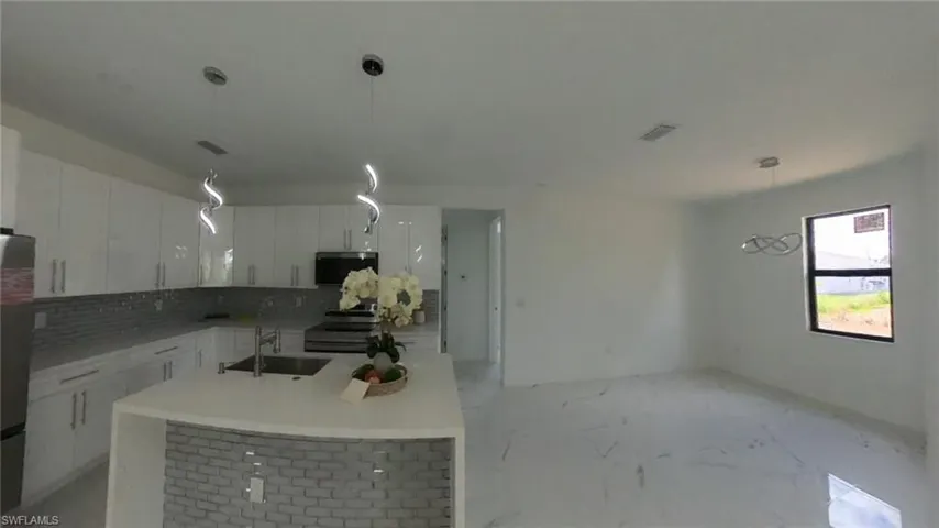 Kitchen featuring visible vents, a sink, white cabinets, tasteful backsplash, and appliances with stainless steel finishes