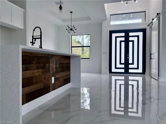 Foyer entrance featuring a raised ceiling, a barn door, and an inviting chandelier