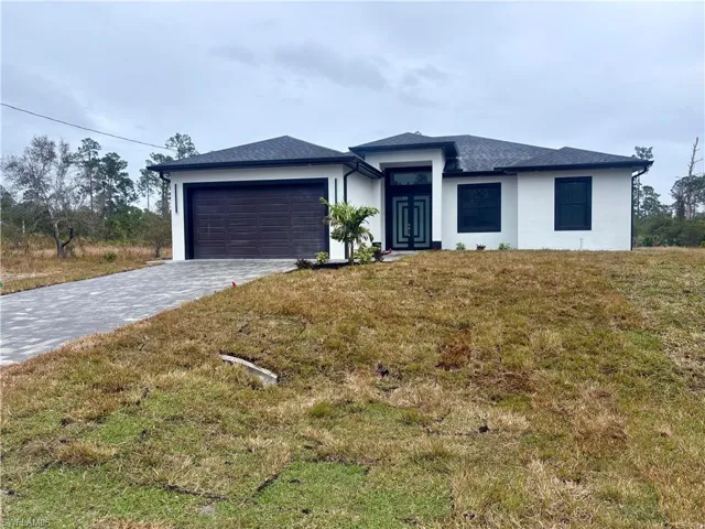 View of front facade featuring a garage and a front lawn