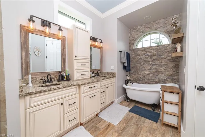 Bathroom with double vanity, wood finished floors, a soaking tub, and a sink