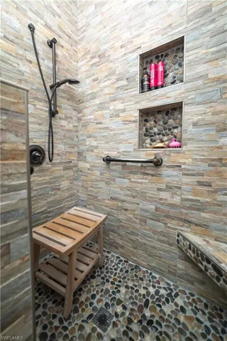 Full bathroom featuring stone floors and tiled shower