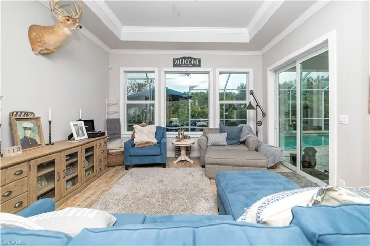 Living area featuring ornamental molding, wood finished floors, and a raised ceiling