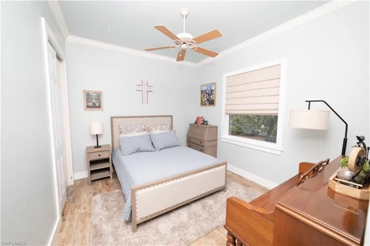 Bedroom with baseboards, crown molding, and wood finished floors