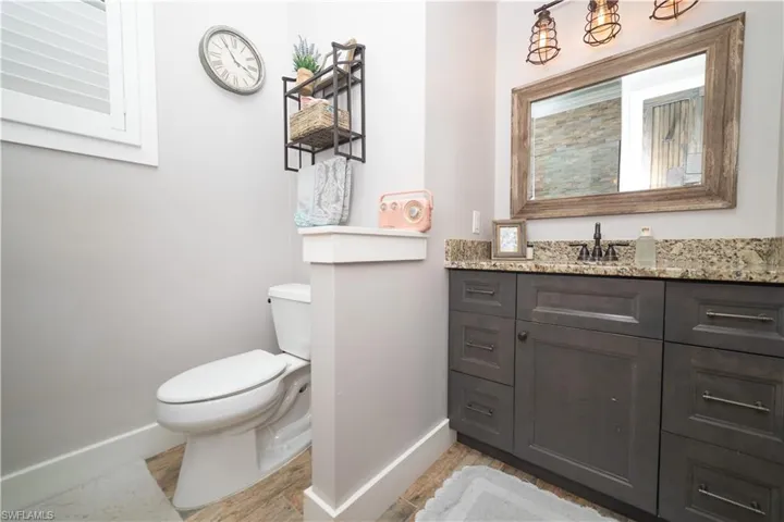 Bathroom with wood finished floors, toilet, and baseboards