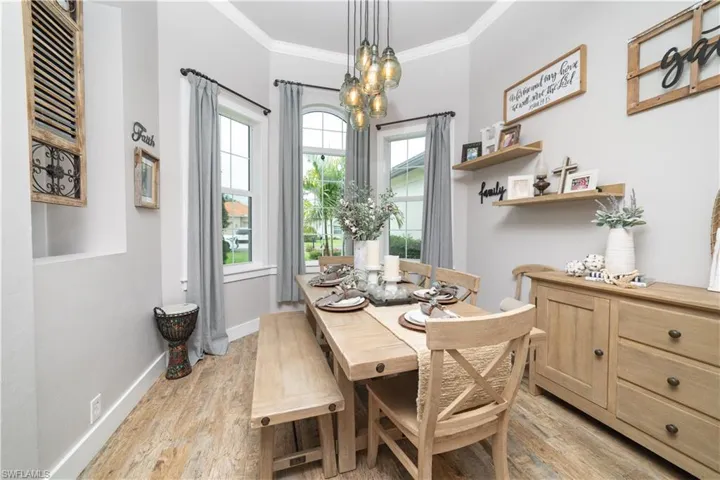 Dining room with light wood-type flooring, a notable chandelier, and ornamental molding