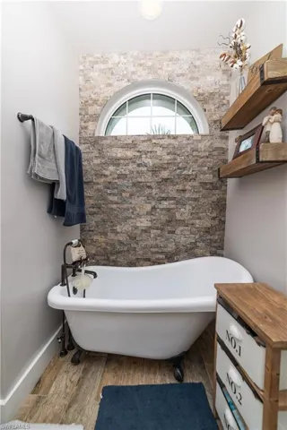 Bathroom with baseboards, a freestanding tub, and wood finished floors